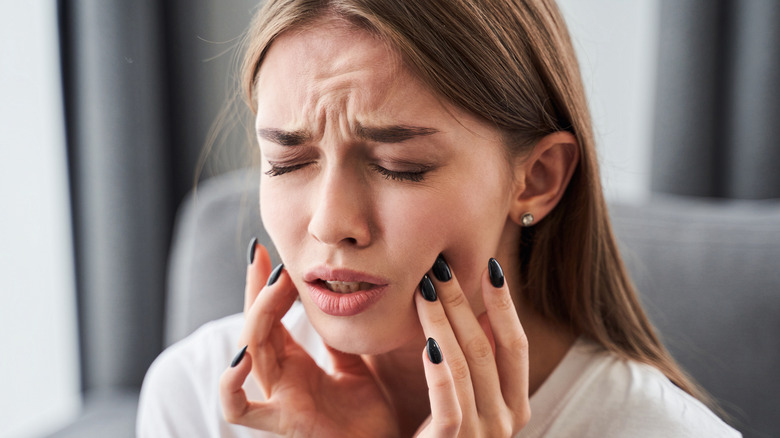 girl with toothache holding cheek in pain