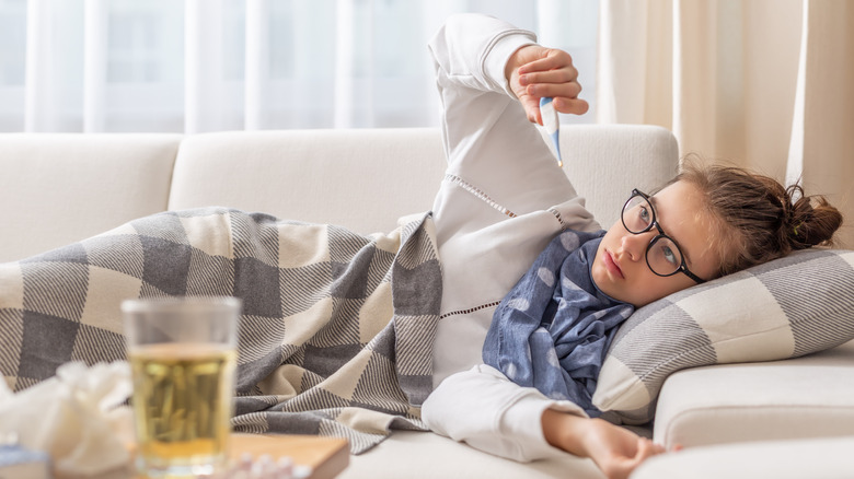 A sick girl checks her temperature