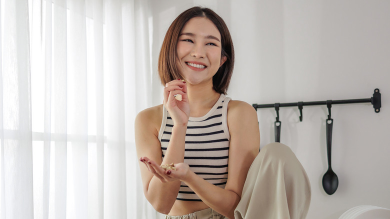 Smiling young woman eating cashews