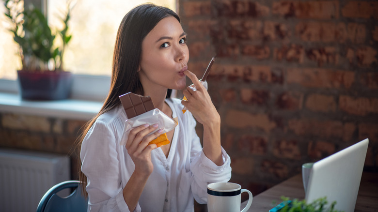 Woman eating chocolate while working