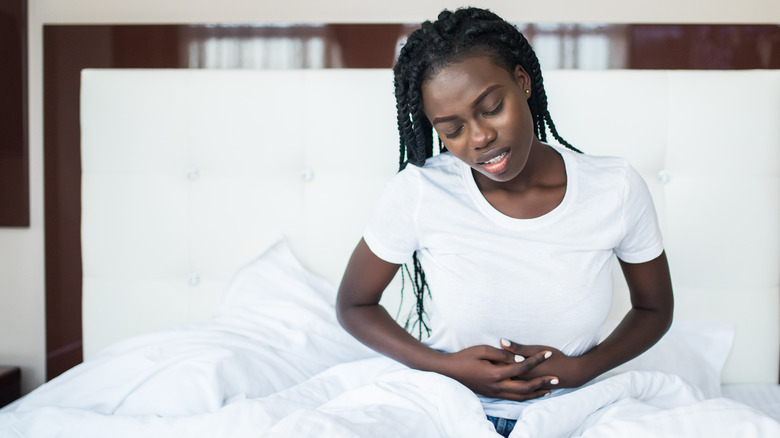 woman in bed with stomach pain