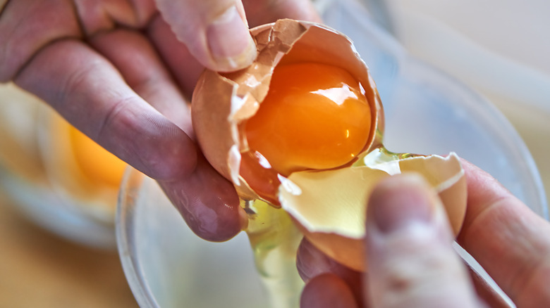 Hands separating the egg yolk from egg white