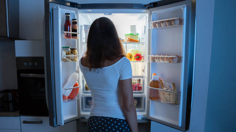 woman looking in fridge late at night