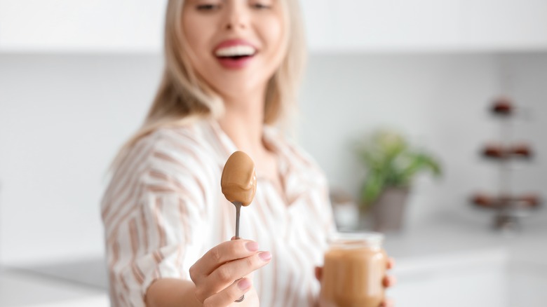 woman holding a spoonful of peanut butter