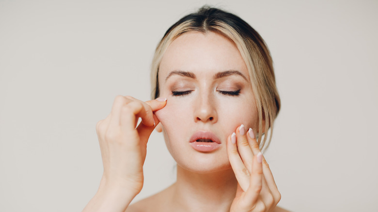 woman lightly massaging and pinching her face 