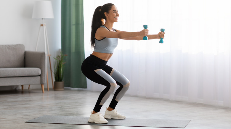 Woman doing squats with dumbbells