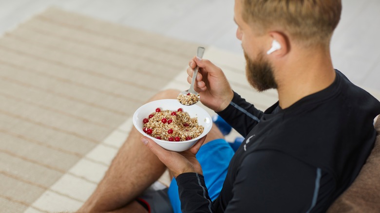 Man with earbud eating from bowl