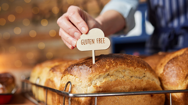 Baker putting a gluten free sign in a loaf of bread 