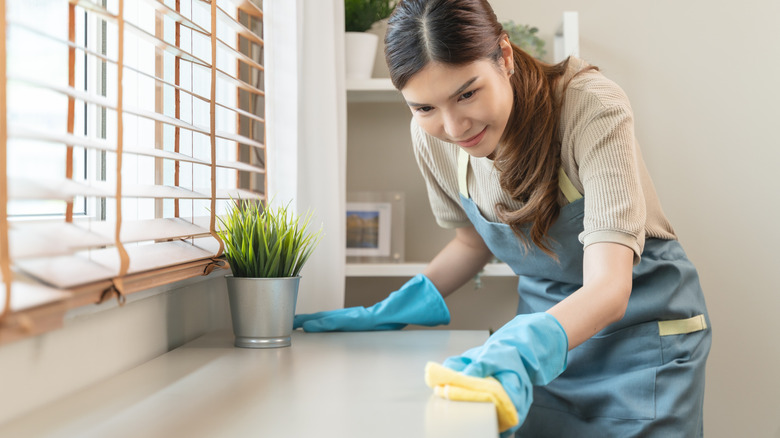 A woman sanitizing kitchen surfaces