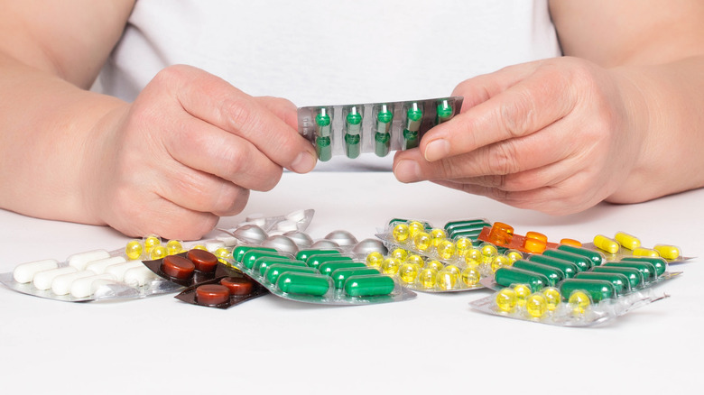 woman's hands holding several types of pills