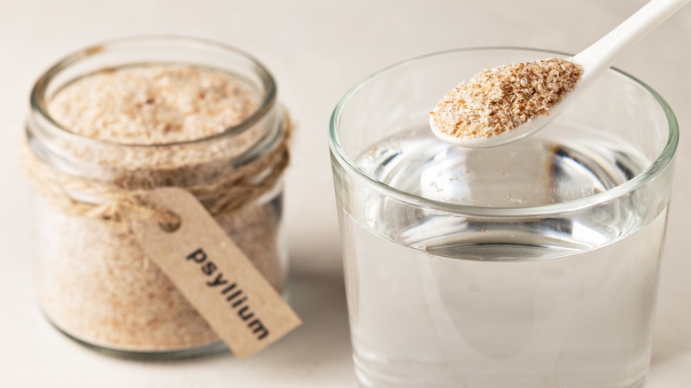 jar of psyllium husk next to a glass of water