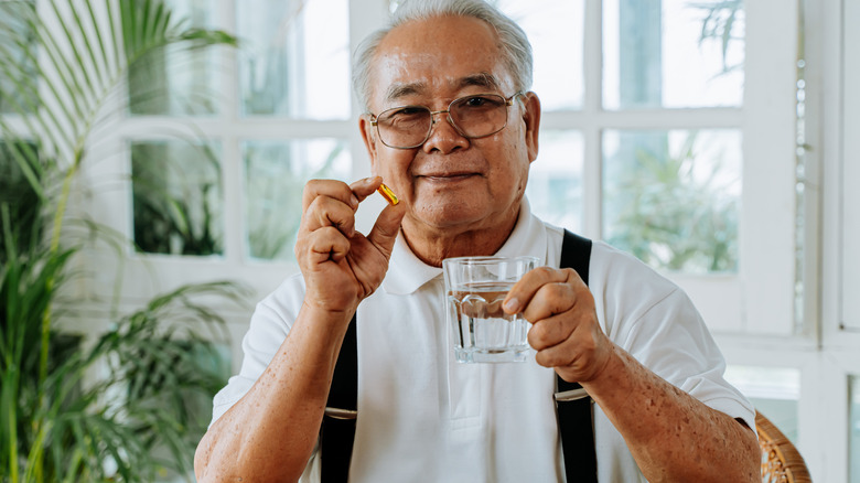 Man holding capsule and water glass