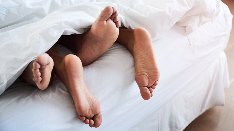 two pairs of feet poking out from comforter