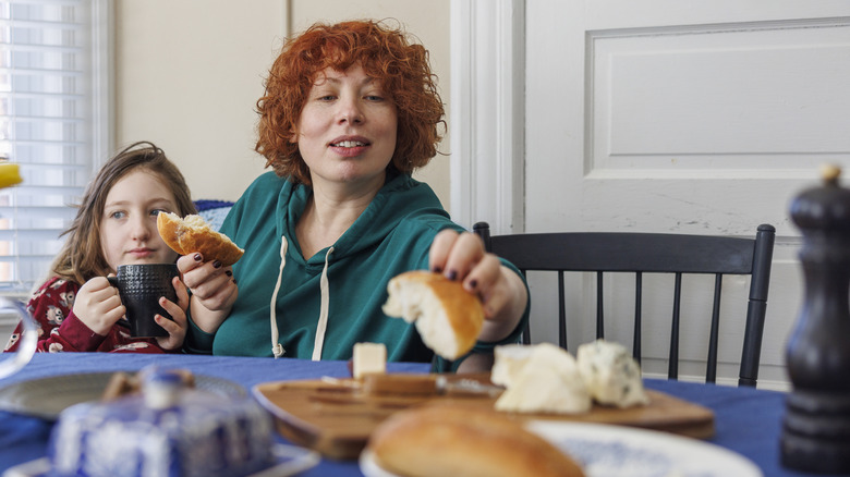 A woman and child eating bread and aged cheese