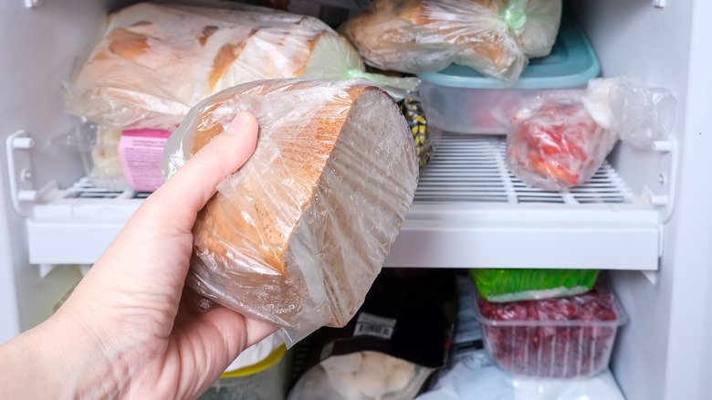 A man putting bread in the freezer