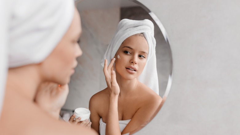 woman applying cream to face