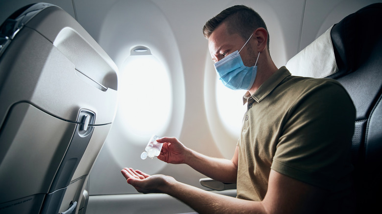 Man using sanitizer on airplane