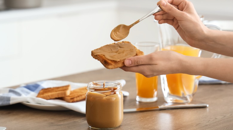 woman spooning peanut butter on toast