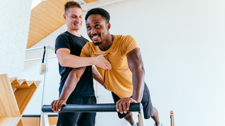 Man practicing reformer Pilates with instructor