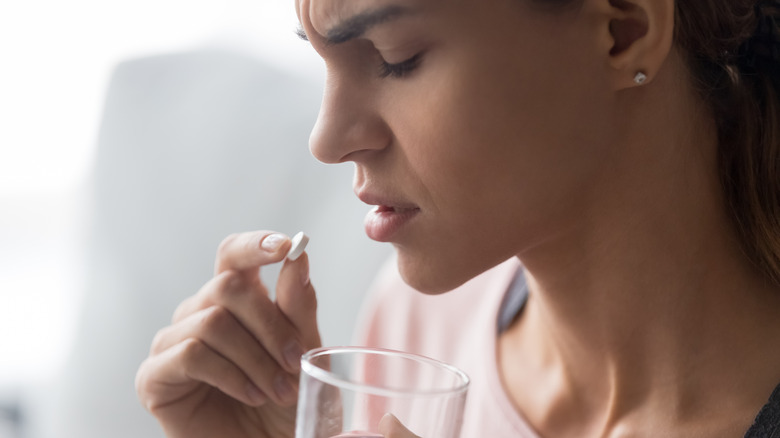 Closeup of woman in pain taking ibuprofen