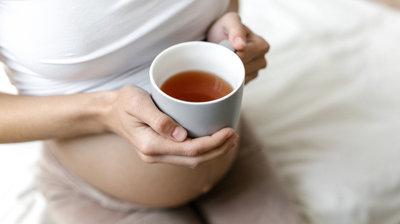 pregnant woman holding tea mug