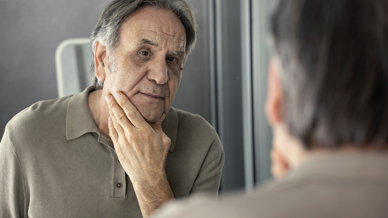 Man examining skin in mirror