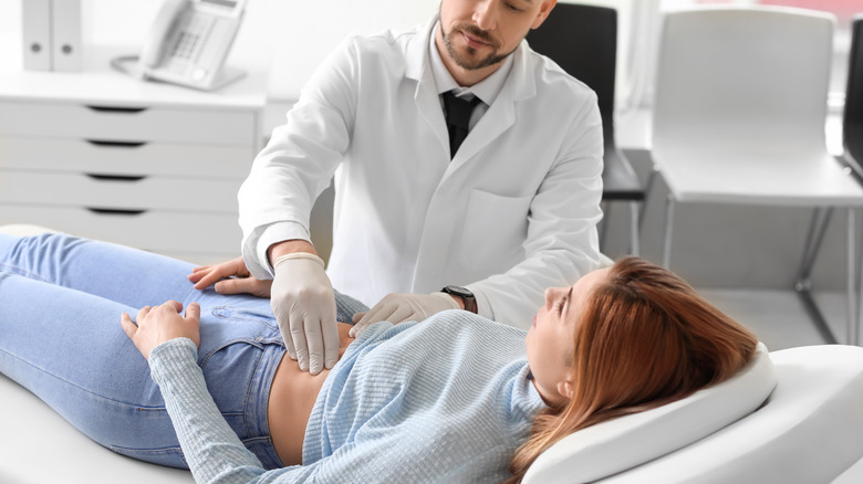 doctor palpating woman's stomach