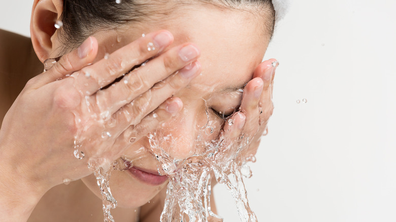 young woman splashing water on her face 