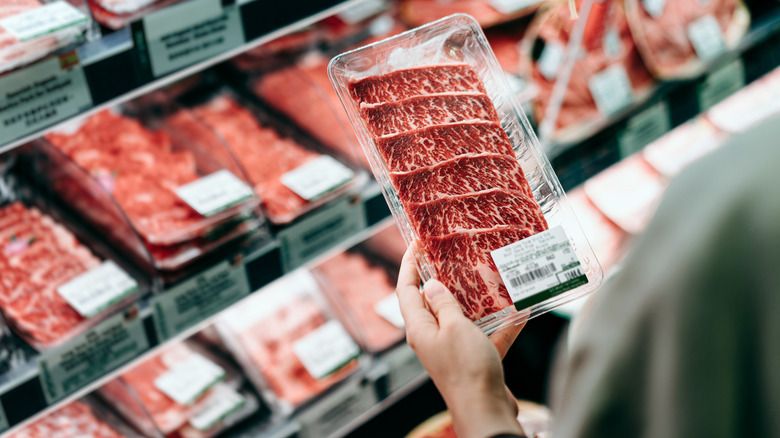 woman holding meat package at grocery store