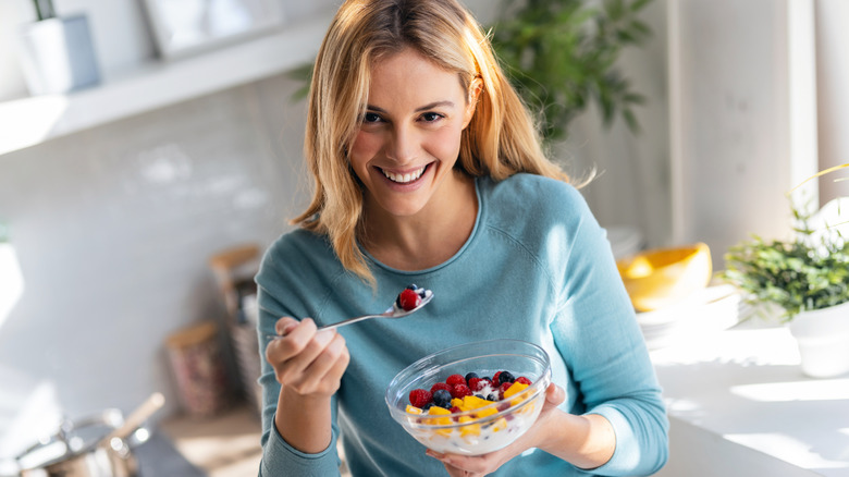 A woman eating a bowl of fruit