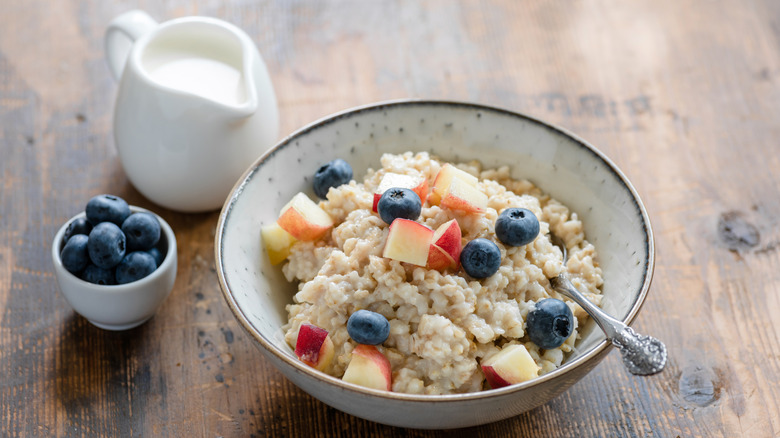 A bowl of oatmeal topped with apples and berries