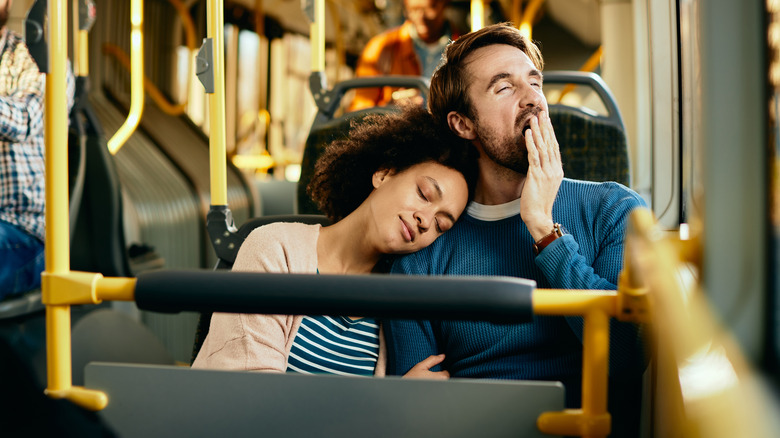 Sleepy couple leaning against one another on public shuttle