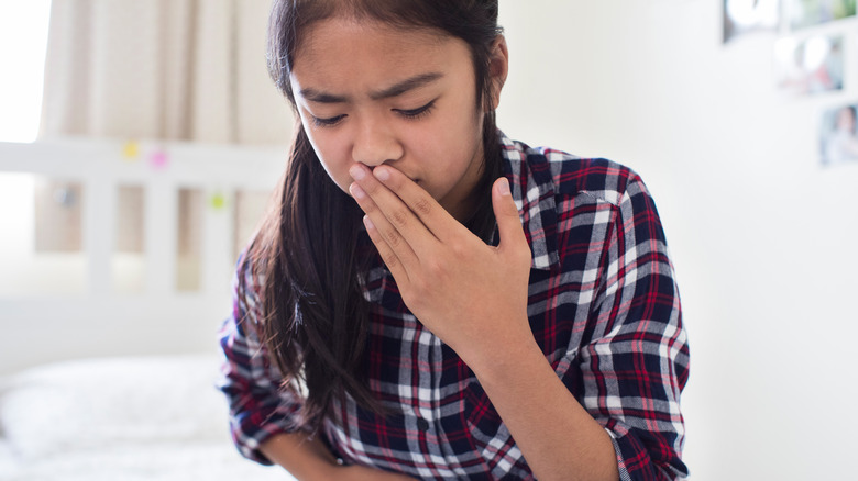 girl feeling nauseous and covering mouth