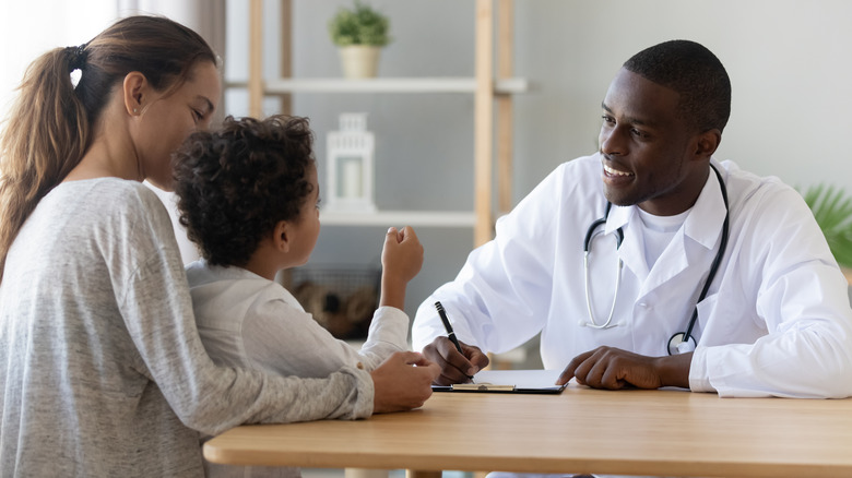 Parent and child talking to smiling doctor
