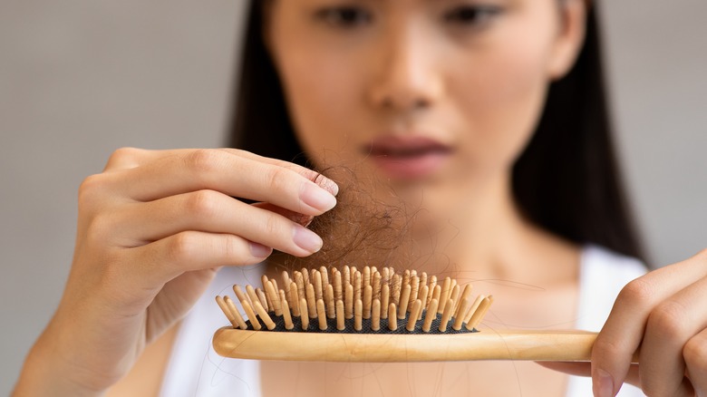 asian woman examines hair in brush