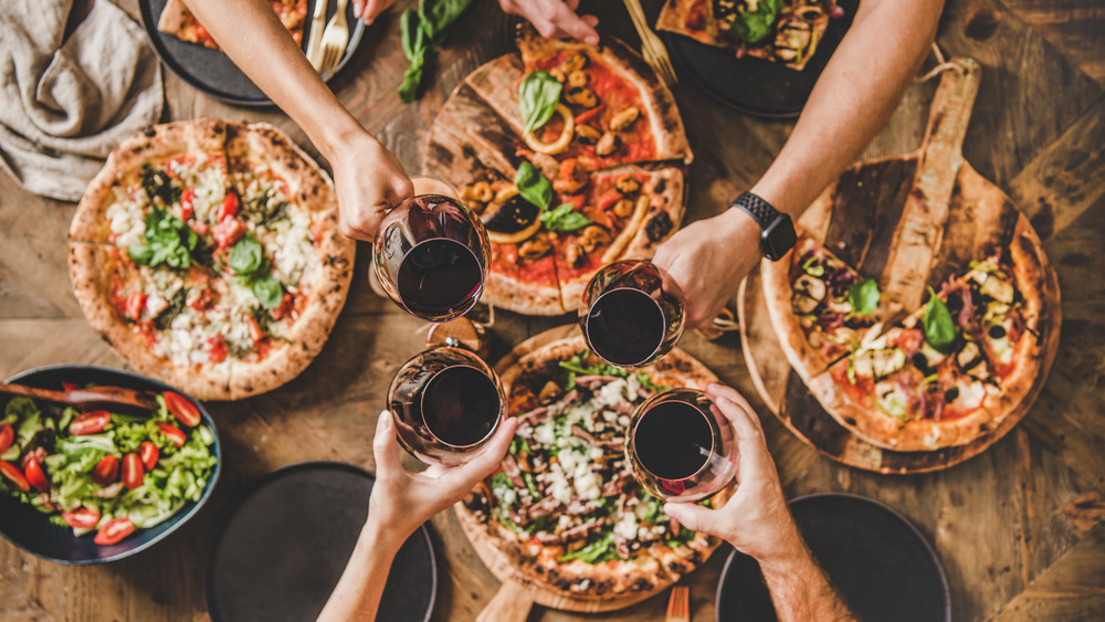 Wine glasses held over pizzas