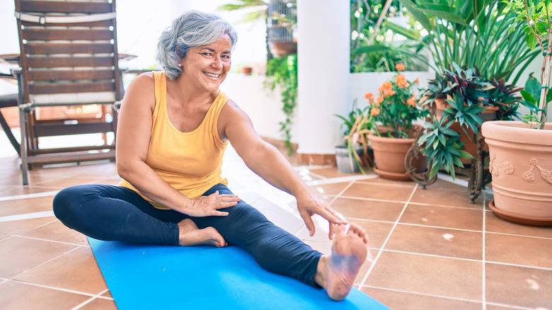 Older woman stretching on yoga mat