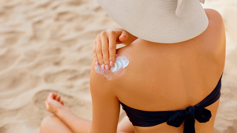 A woman puts on sunscreen