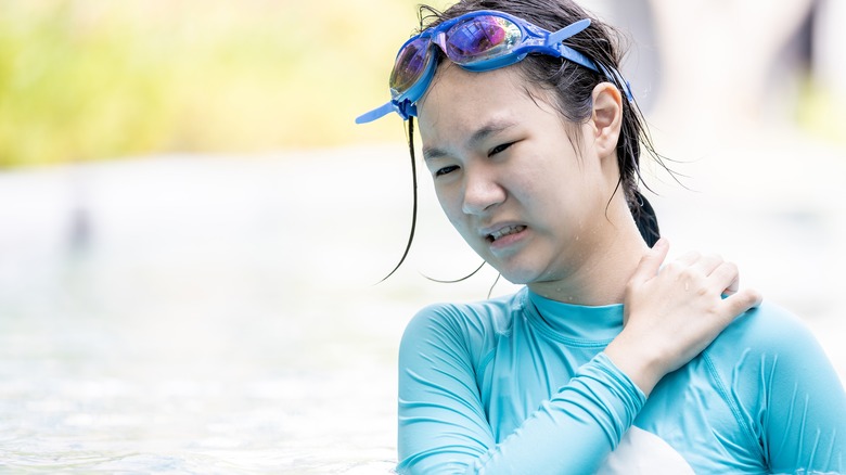 woman near water scratching swimmer's itch rash