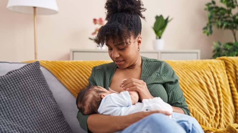 a mother breastfeeds her son on the sofa