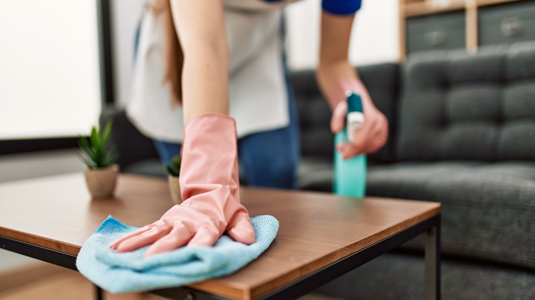 person disinfecting living room table