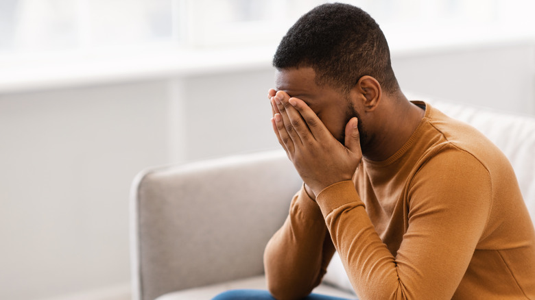 Man sitting on couch crying