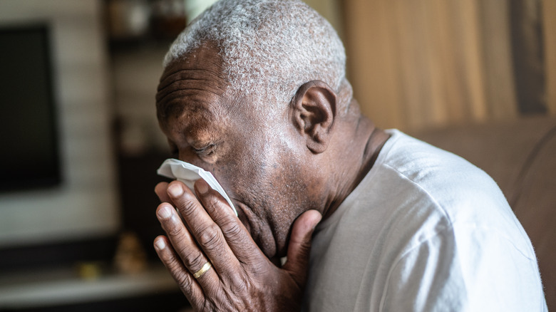 Older man blowing nose