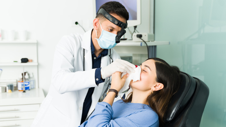 Doctor treating patient with nose bleed