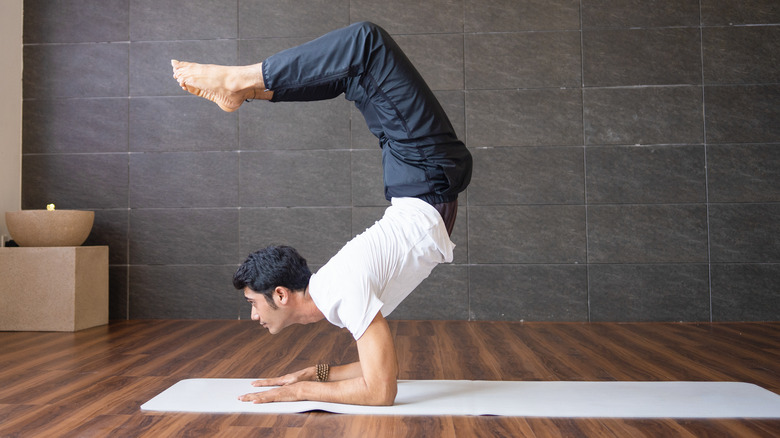 man doing scorpion yoga pose