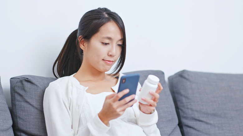 woman reading prescription label and research on her phone