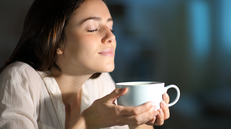 A woman smelling her coffee