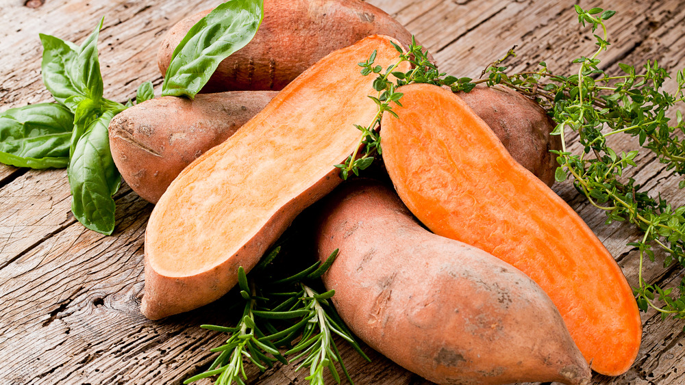 Sweet potatoes and greens on wooden background