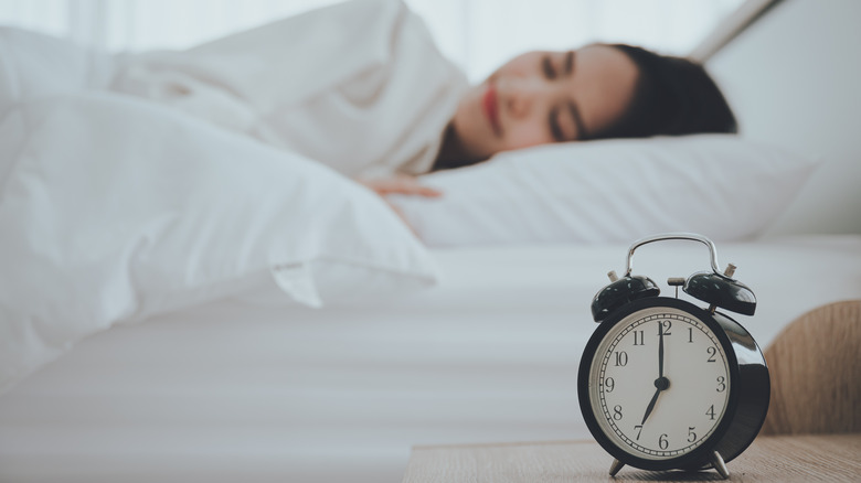 woman asleep by a clock