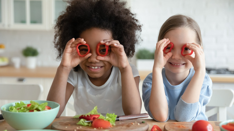 two children holding red bell peppers